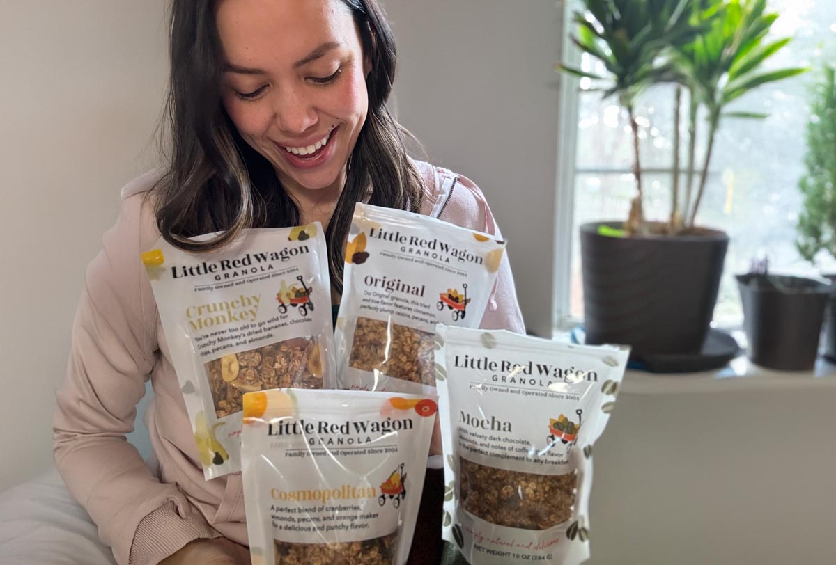 Woman holding packages of Little Red Wagon granola in a home setting