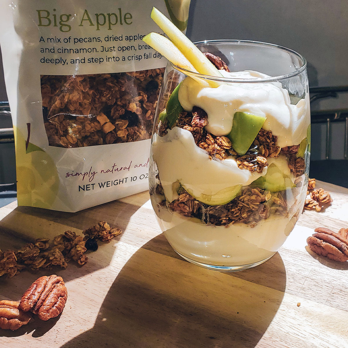 apple pie granola parfait in glass next to Little Red Wagon's Big Apple Granola