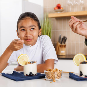 Child eating a dessert with lemon slices in a kitchen setting