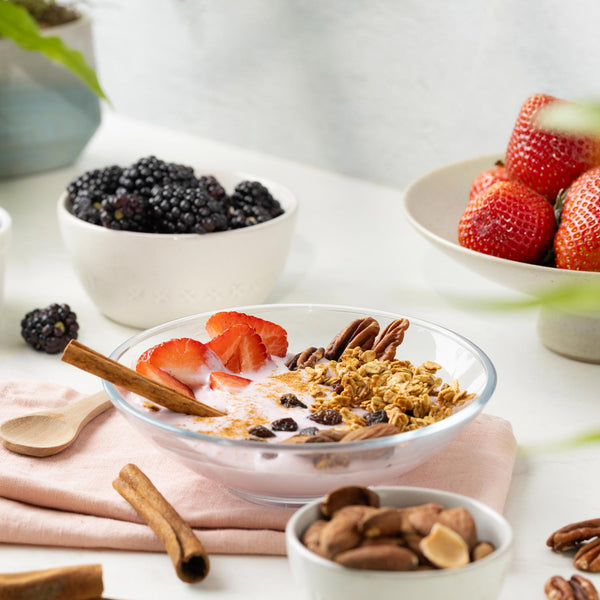 Yogurt bowl with granola, strawberries, and blackberries on a white surface.